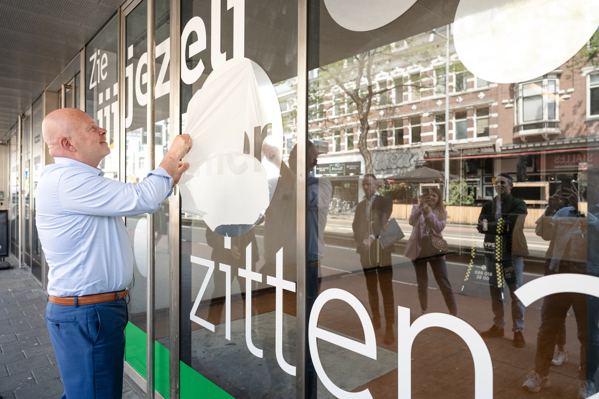 Wethouder Robert Simons onthult de raamsticker op het aangekochte pand aan de Nieuwe Binnenweg. Foto: Laura-anne Grimbergen