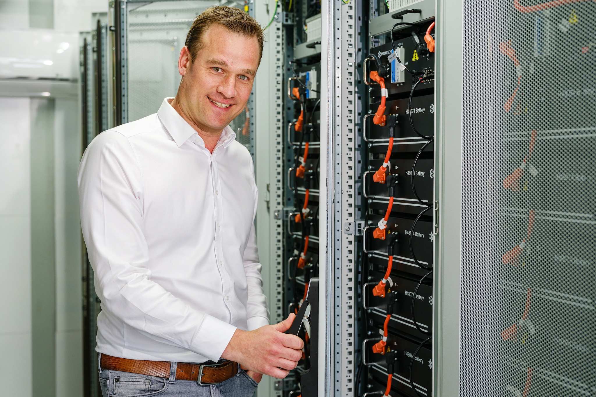 Jeroen Dirkzwager staat in een zeecontainer die is gevuld met tien kasten vol met op elkaar gestapelde batterijen. Beeld: Marlies Wessels. Marlies Wessels. Jeroen Dirkzwager staat in een zeecontainer die is gevuld met tien kasten vol met op elkaar gestapelde batterijen