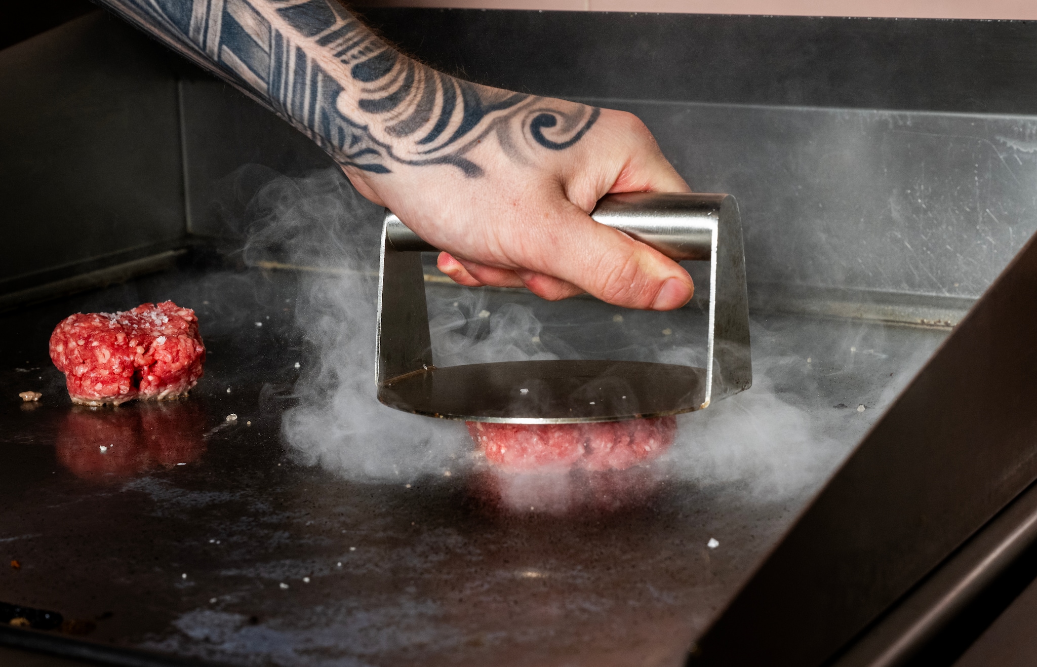 Een smashburger dankt zijn naam aan het smashen op de bakplaat. Een smashburger dankt zijn naam aan het smashen op de bakplaat. Foto: Frank de Roo