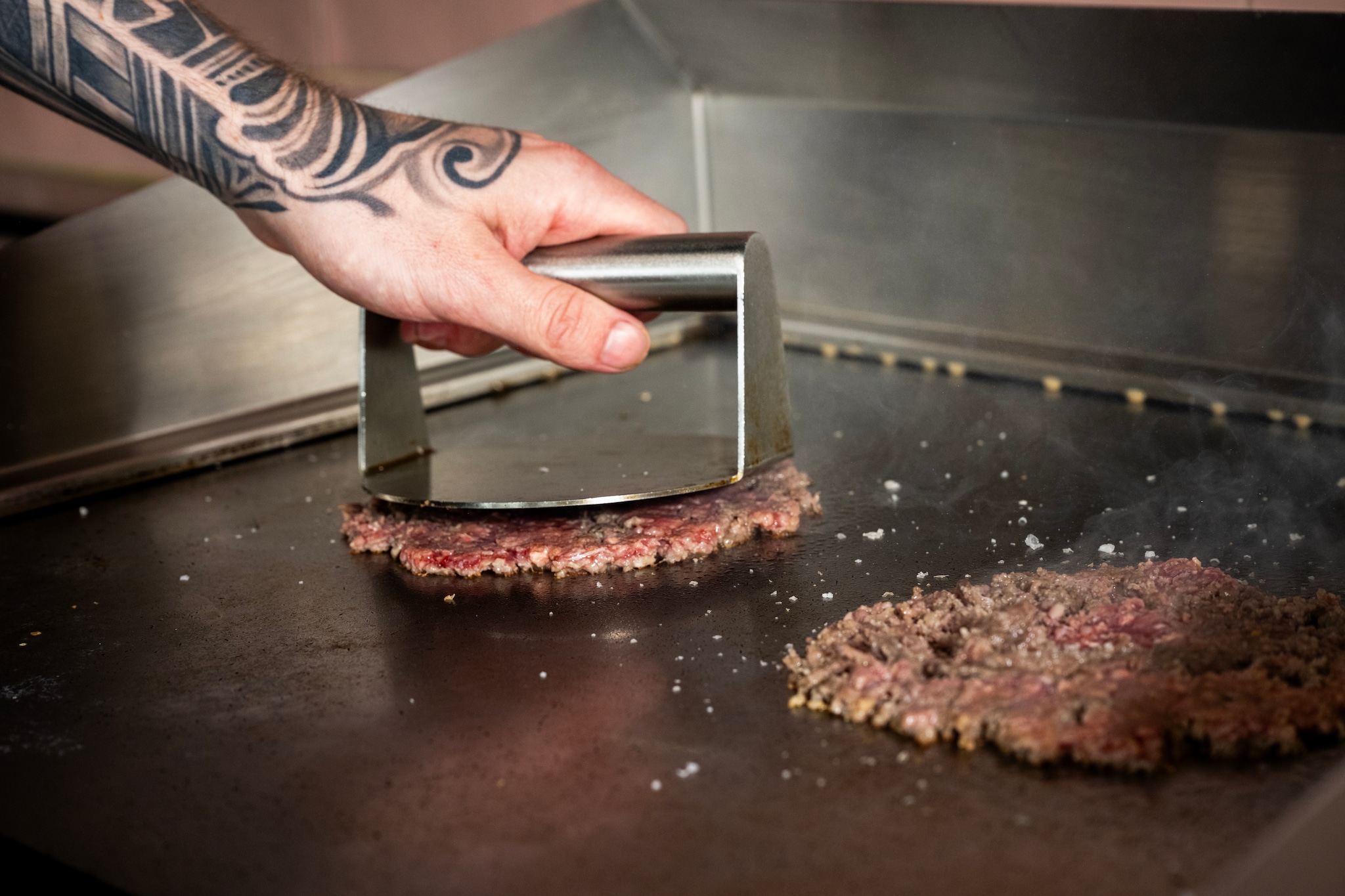 Een smashburger dankt zijn naam aan het smashen op de bakplaat. Een smashburger dankt zijn naam aan het smashen op de bakplaat. Foto: Frank de Roo