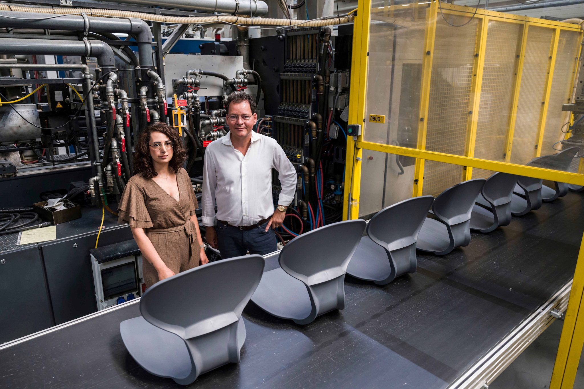 Directeur Hans Kolnaar en HR-adviseur Linda Balci aan de band met zittingen voor schoolstoeltjes: cobots moeten in de toekomst helpen bij het inpakken. Directeur Hans Kolnaar en HR-adviseur Linda Balci aan de band met zittingen voor schoolstoeltjes Foto: Lars Smook