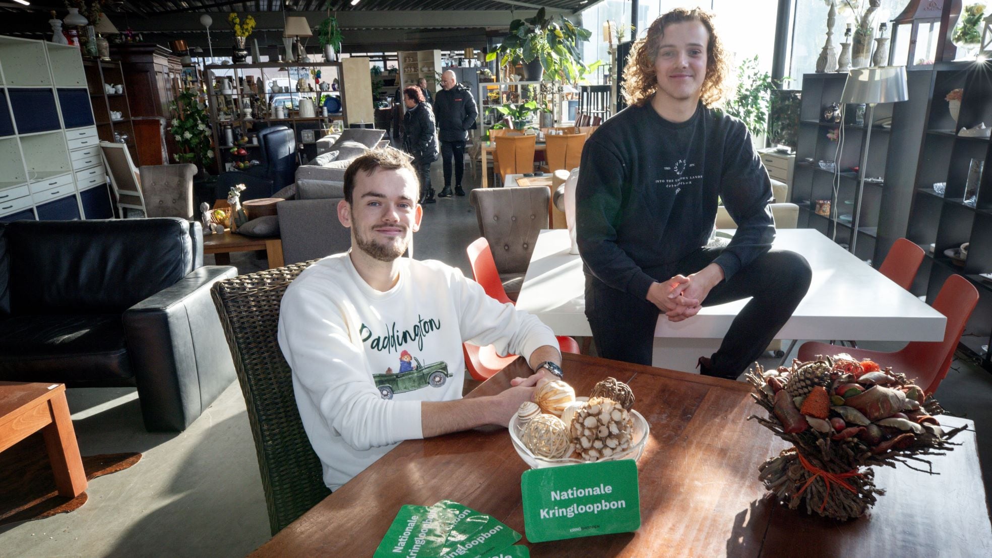 Koen Dierink (links) en Stijn Smits met de kringloopcadeaubon in kringloopwinkel Henkie’s Hoekie. Koen Dierink (links) en Stijn Smits met de kringloopcadeaubon in een kringloopwinkel. Foto: Joyce van Belkom/Pix4Profs