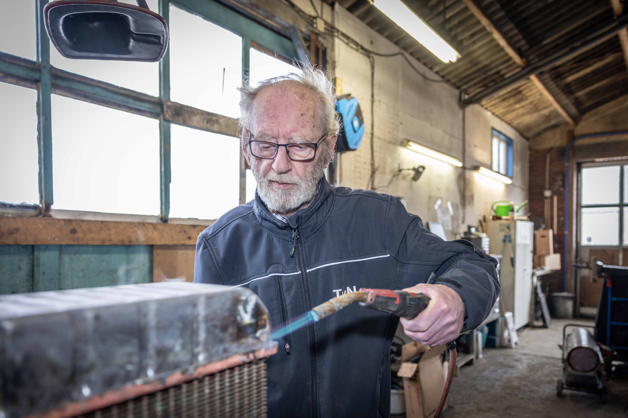 Teunis van Nes aan het werk in zijn tijdelijke werkplaats, pal naast de plek waar zijn eigenlijke bedrijf in vlammen opging. Teunis van Nes aan het werk in zijn tijdelijke werkplaats, pal naast de plek waar zijn eigenlijke bedrijf in vlammen opging. Foto: Marcelle Davidse