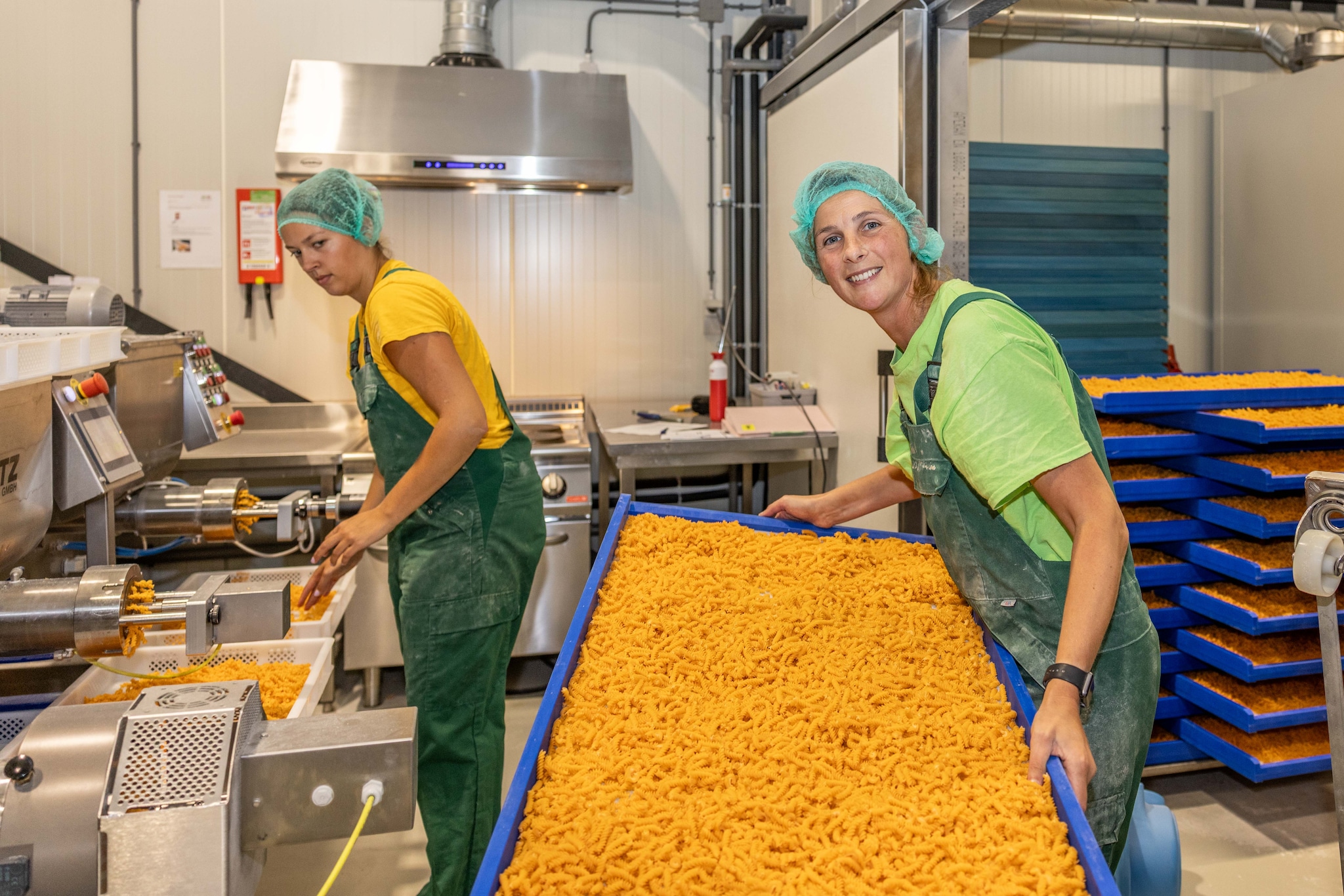 Linsie Meijer (rechts) en Lotte Ruisaard zijn bezig aan de productie van vandaag: pasta waaraan verse paprika is toegevoegd. Linsie Meijer (rechts) en Lotte Ruisaard zijn bezig aan de productie van vandaag: pasta waaraan verse paprika is toegevoegd. Foto: Marcelle Davidse
