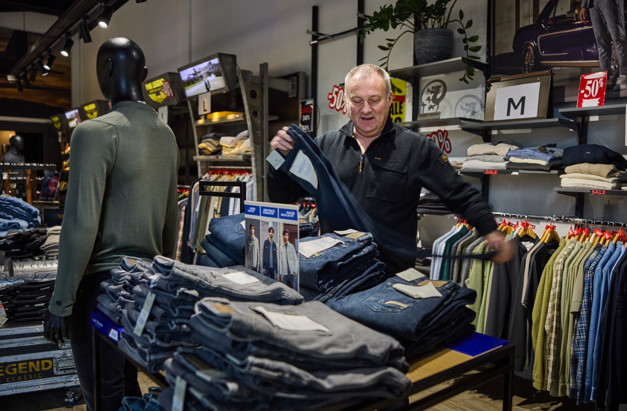 Leegverkoop bij failliete kledingzaak J22: eigenaar Dennis vouwt de jeans op Leegverkoop bij failliete kledingzaak J22: eigenaar Dennis vouwt de jeans op. Foto: Jan de Groen