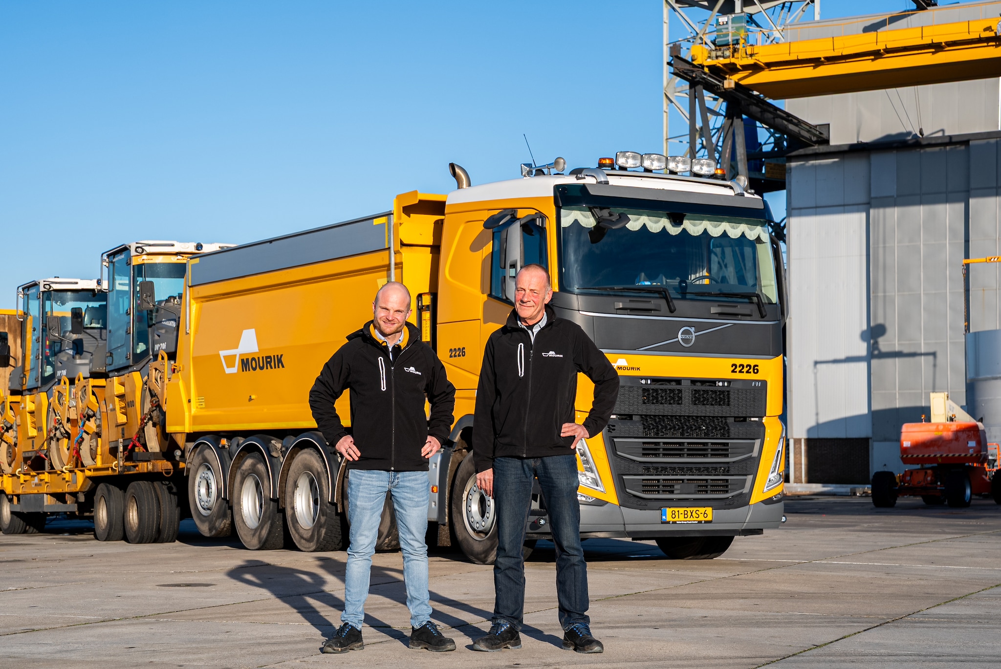 Zoon Toni en vader Jan den Hartog voor een asfaltkieper met een aanhanger vol walsen.