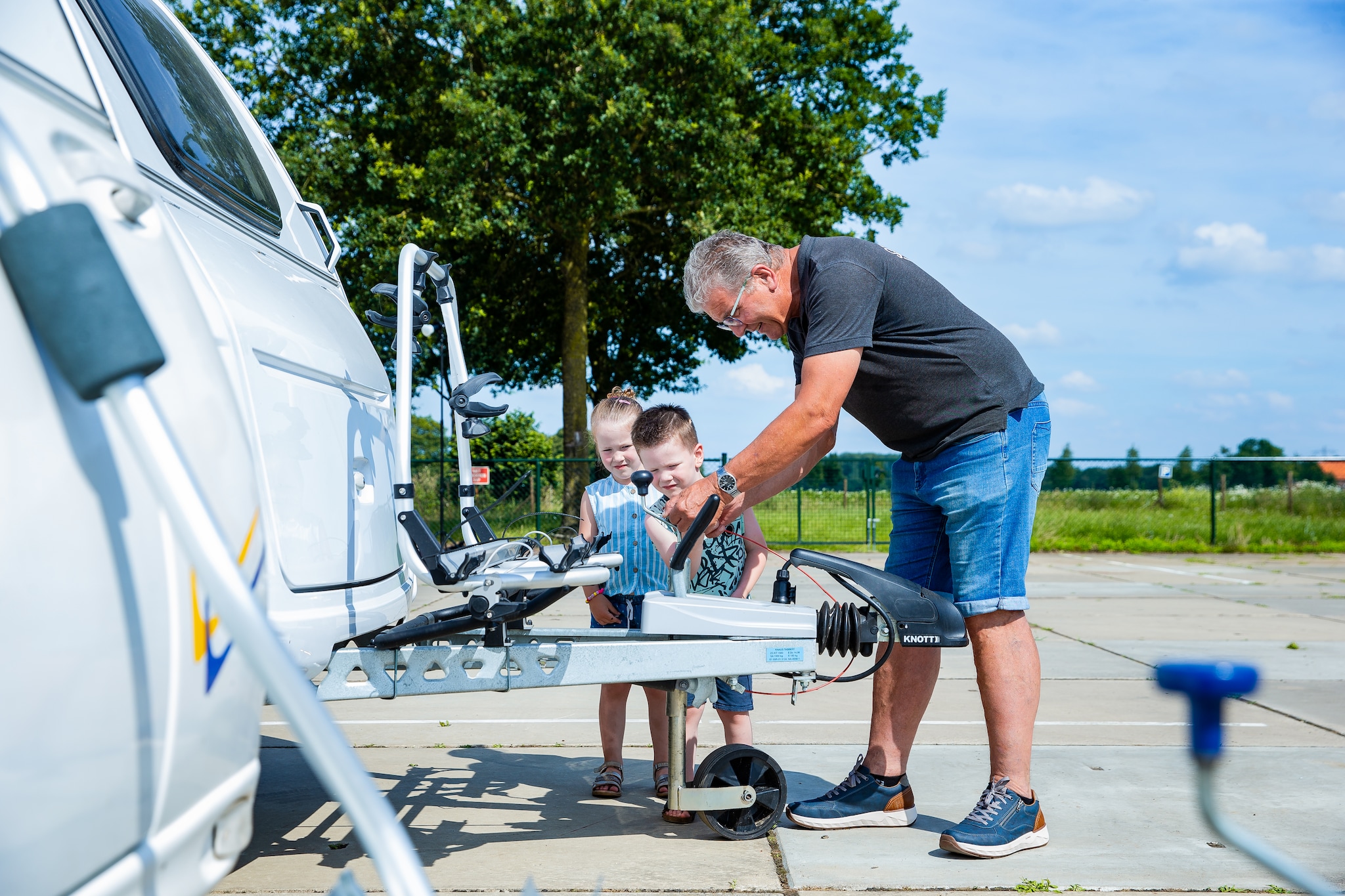 Kleinkinderen Floor en Tijn helpen opa Joost mee met het vastzetten van de caravan. Foto: David van Haren