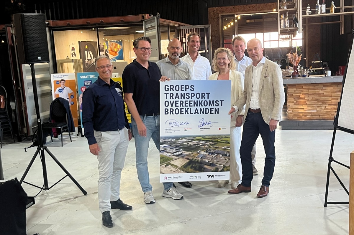 Frank Wiersma (links midden achter het bord) met andere ondernemers en de netbeheerder ondertekenden de groepstransportovereenkomst voor de energiehub Broeklanden.