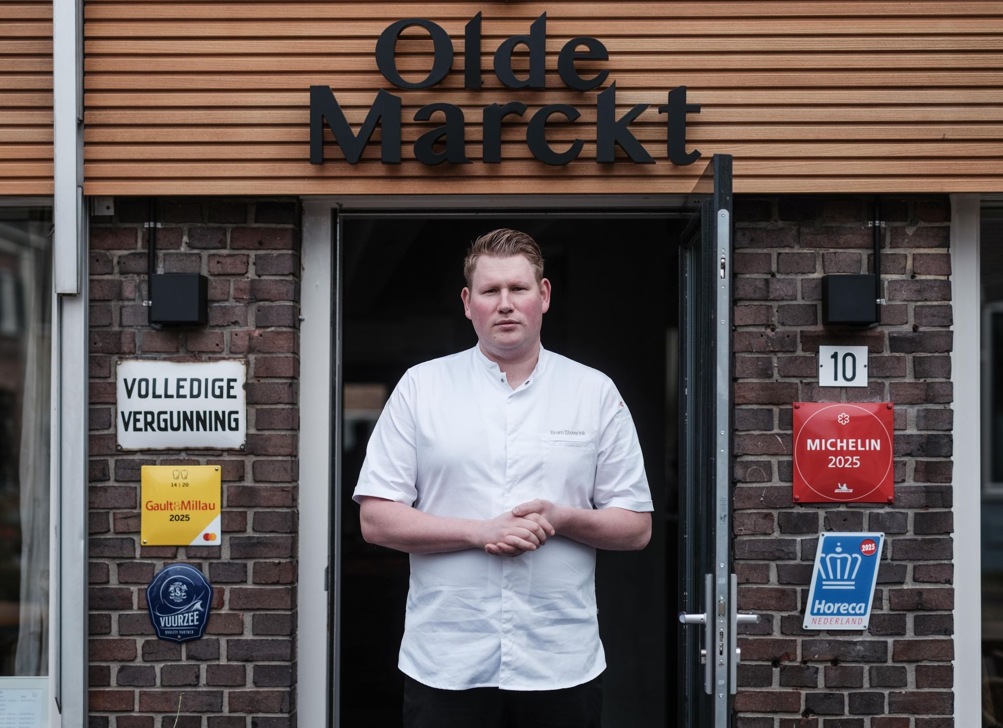 Bram Stoverink voor de ingang van Olde Marckt, met naast hem aan de gevel die felbegeerde Michelinster. Foto: Jan Ruland van den Brink