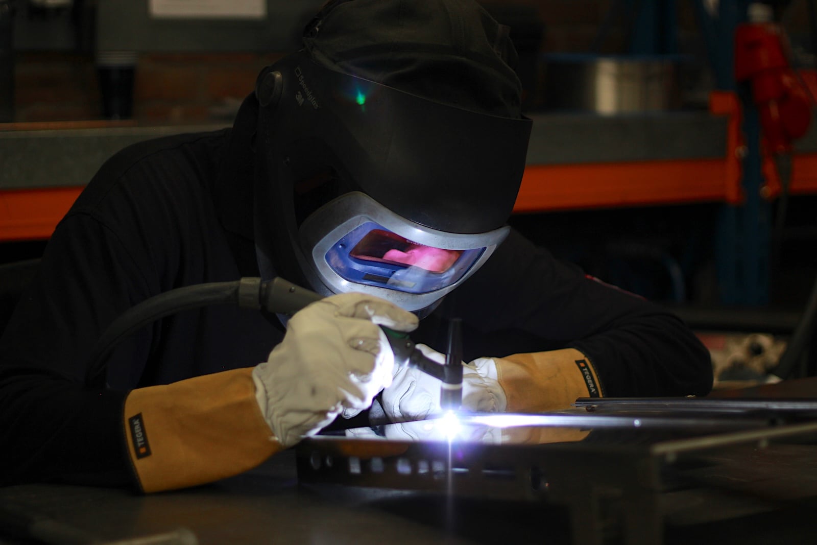 Metaalbewerker van GOMA last metalen onderdelen aan elkaar in een werkplaats.