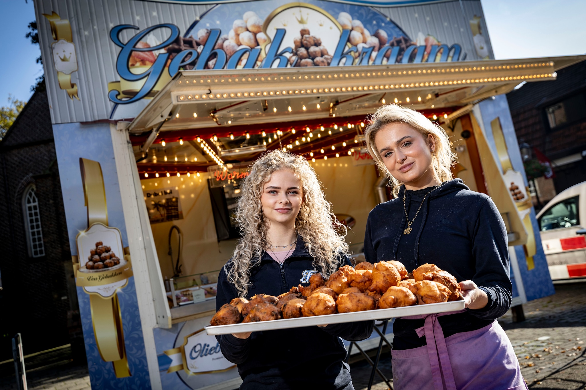 De zussen Femke (links) en Joan Oude Bekke voor hun opvallende oliebollenkraam.